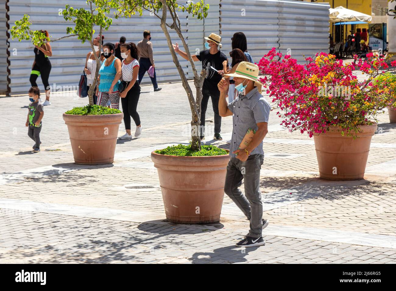 Kubanische Menschen und Touristen sind auf der Plaza Vieja in der Altstadt von Havanna zu sehen. Ein metallischer Zaun im Hintergrund zeigt, dass einige Gebäude rekonstruiert sind Stockfoto