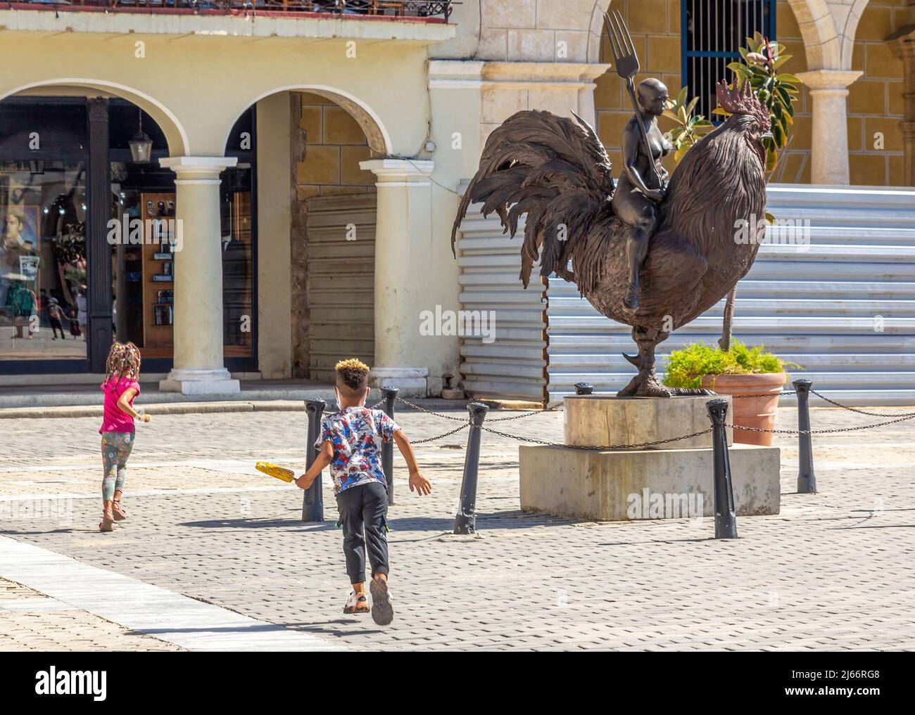 Kubanische Kinder, eines mit Maiskolben, werden bei der Skulptur 'Viaje Fantastico' auf der Plaza Vieja in Alt-Havanna beim Laufen gesehen. Stockfoto