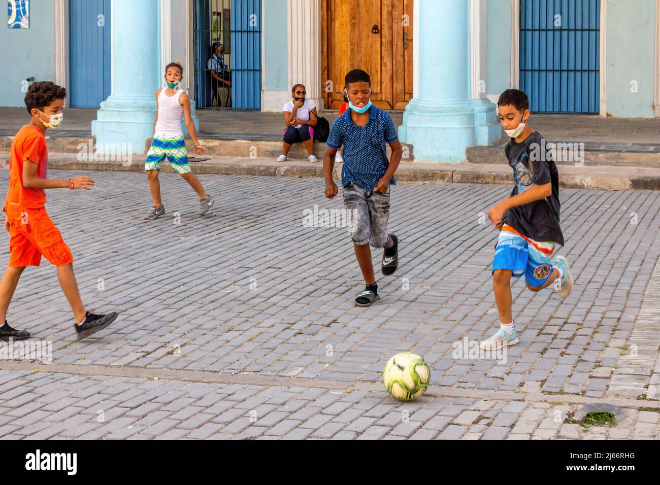 Kubanische Kinder mit Gesichtsmasken spielen auf der Plaza Vieja in Alt-Havanna Fußball. Stockfoto