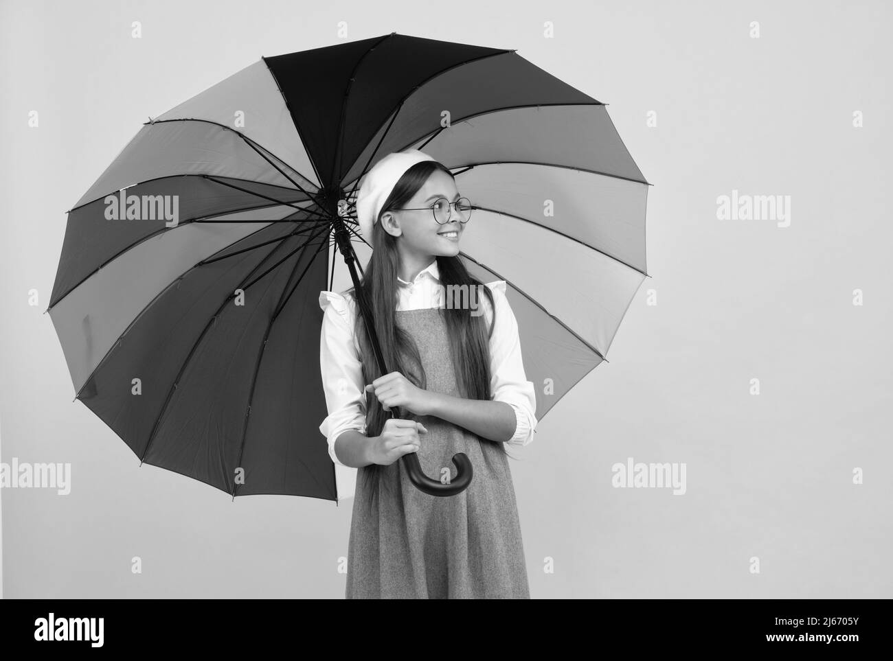 Happy teen Mädchen in Baskenmütze unter bunten Regenschirm für Regenschutz in der Herbstsaison, Kindheit. Stockfoto