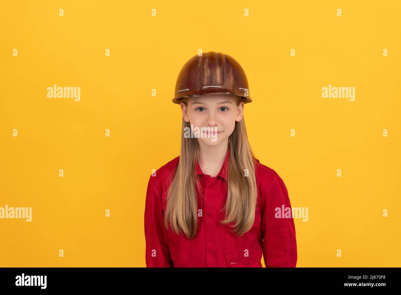 Lächelndes Teenager-Kind im Bauerhelm auf gelbem Hintergrund Stockfoto