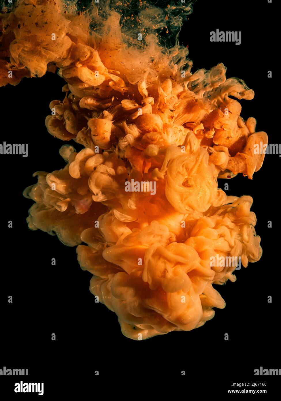 Orangefarbene Acrylfarbe in Wasser auf Schwarz. Stockfoto