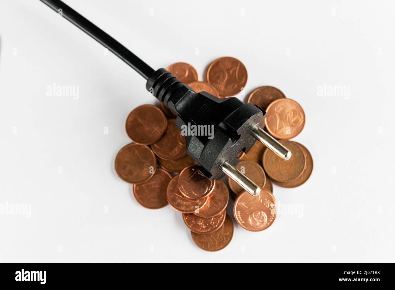Schwarzer Stecker auf Münzen und weißem Hintergrund, Kosten für Strom und teures Energiekonzept Stockfoto