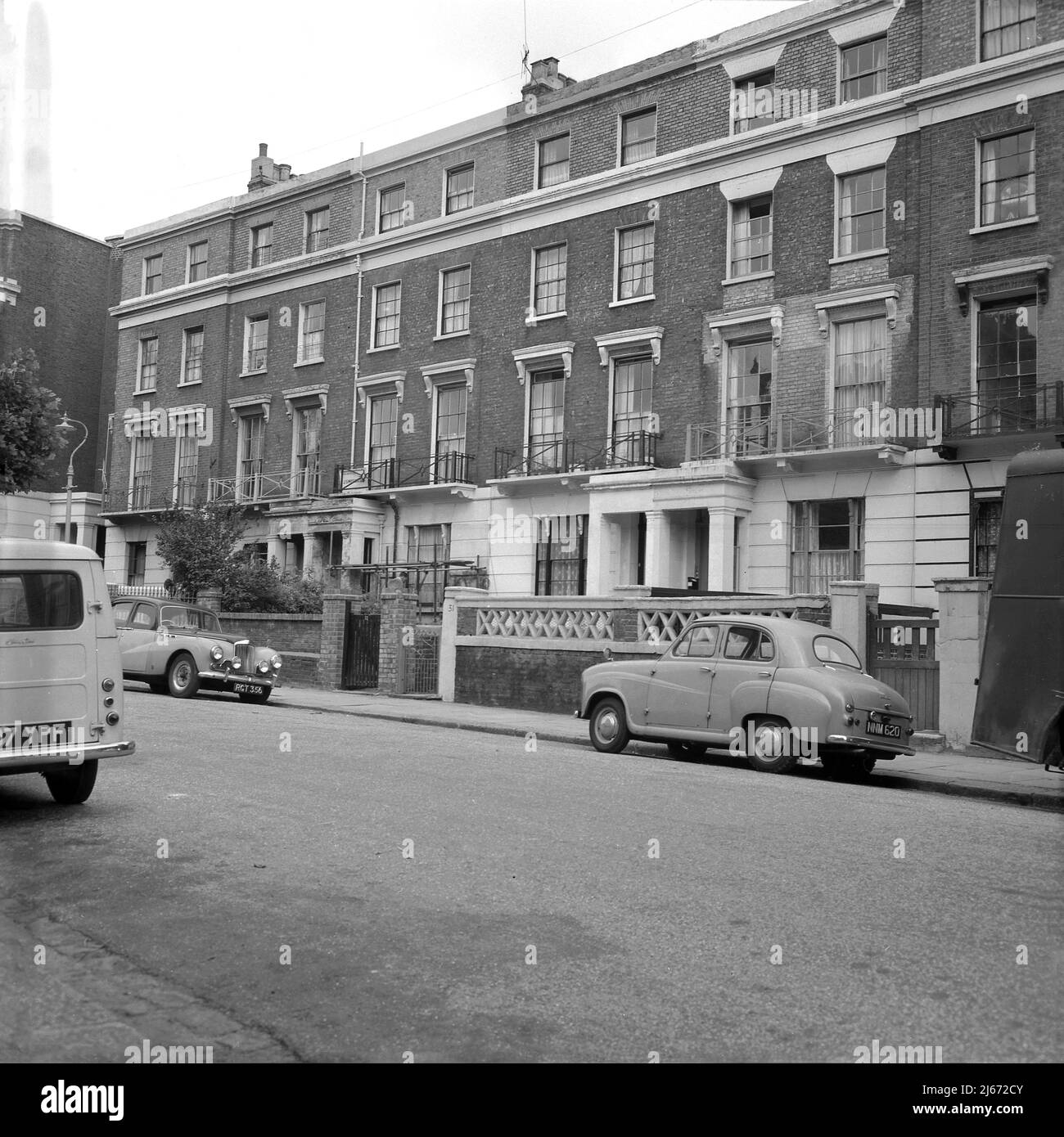1960s, historische Autos der Ära, darunter ein kleiner 4-türiger Austin, der auf einer Straße mit eleganten, aber schäbigen georgianischen Reihenhäusern in der Nähe des Regents Park in London NW1, England, Großbritannien, geparkt war. Stockfoto