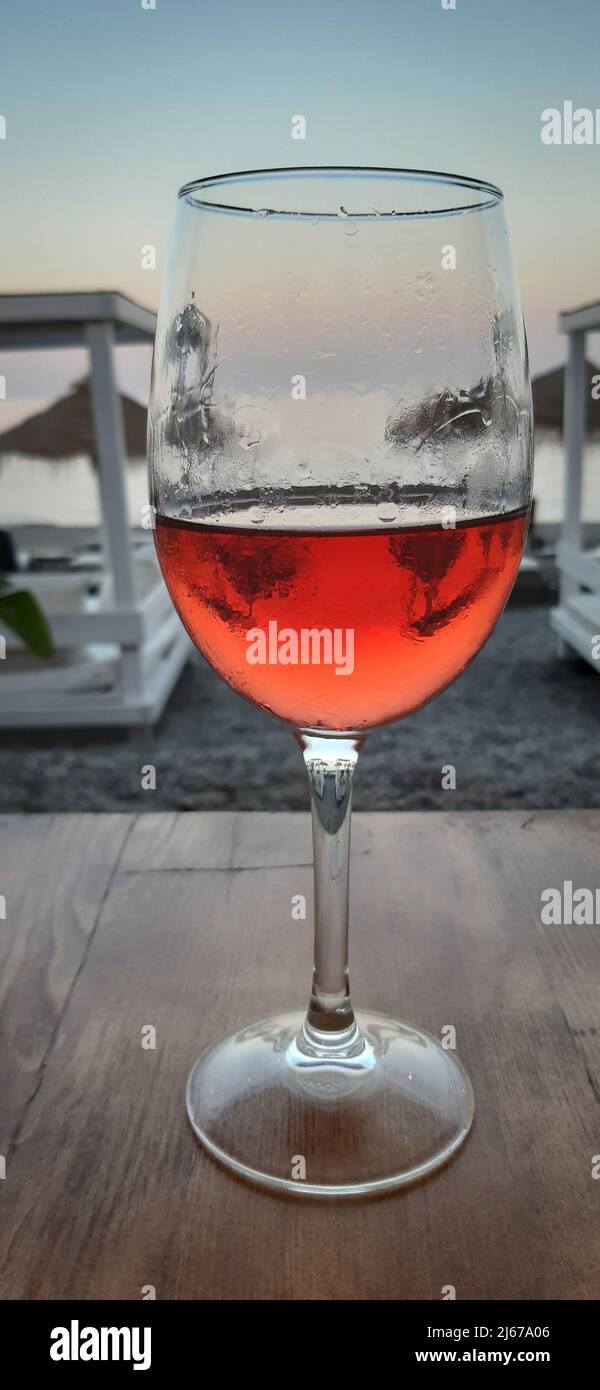 Ein Glas Rotwein am Strand bei Sonnenuntergang Stockfoto