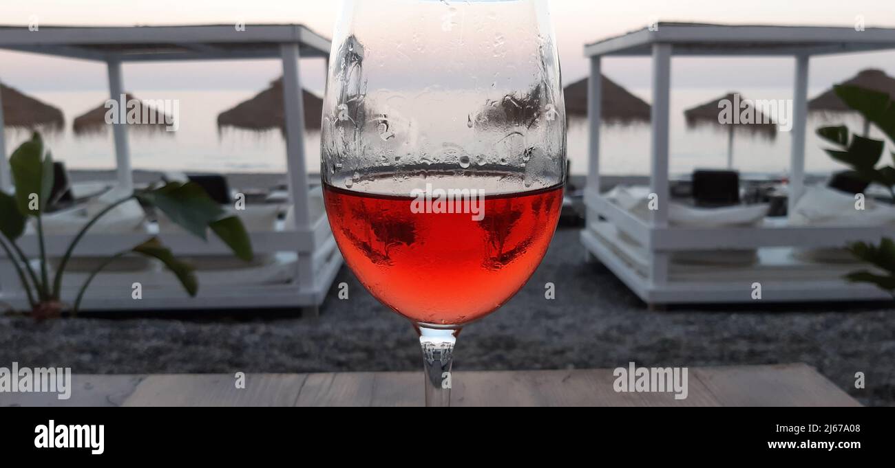 Ein Glas Rotwein am Strand bei Sonnenuntergang Stockfoto