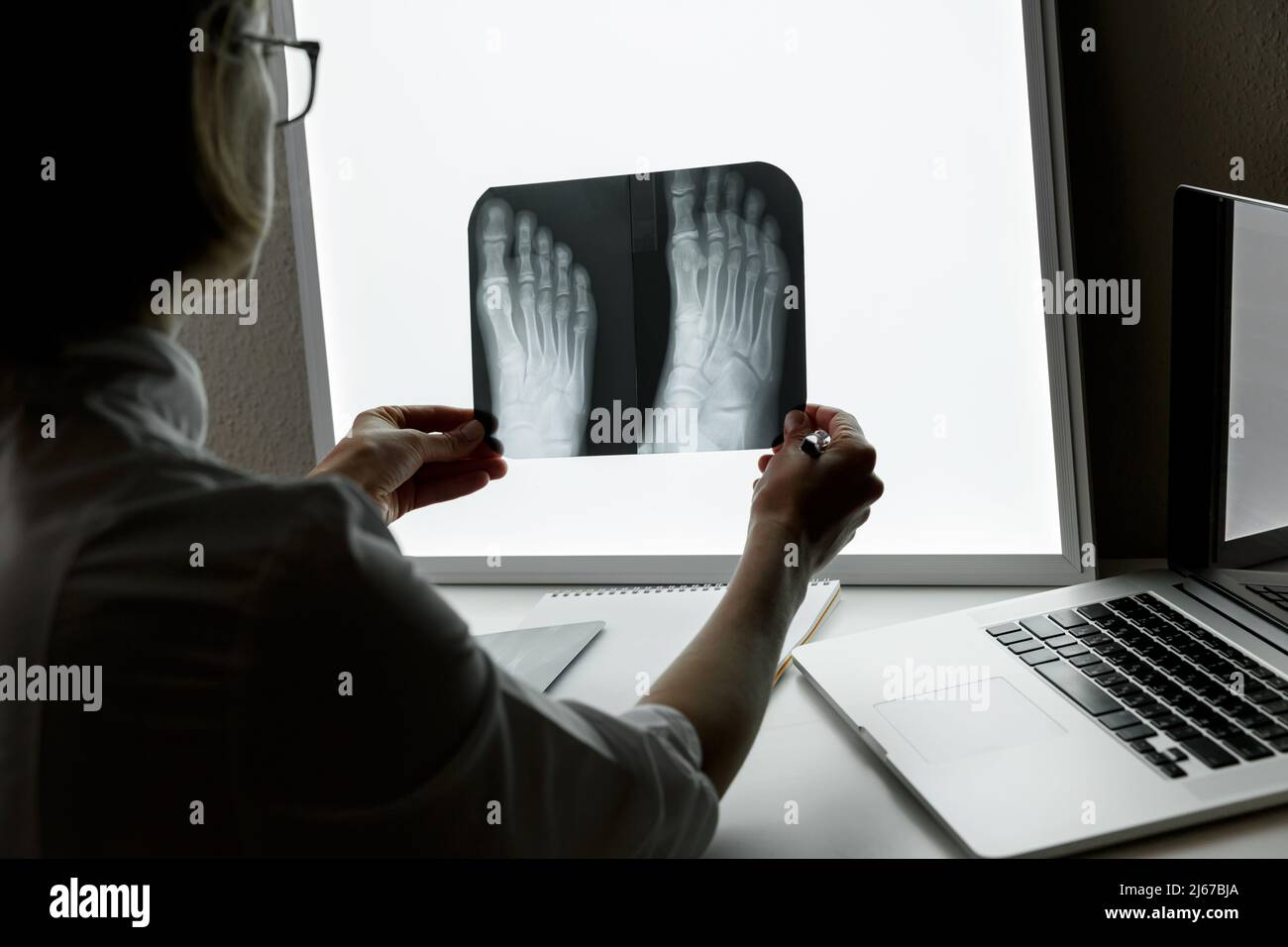 Orthopädischer Chirurg, der eine Röntgenaufnahme des Fußes untersucht. Konzept der Gesundheitsversorgung und Krankenversicherung Stockfoto