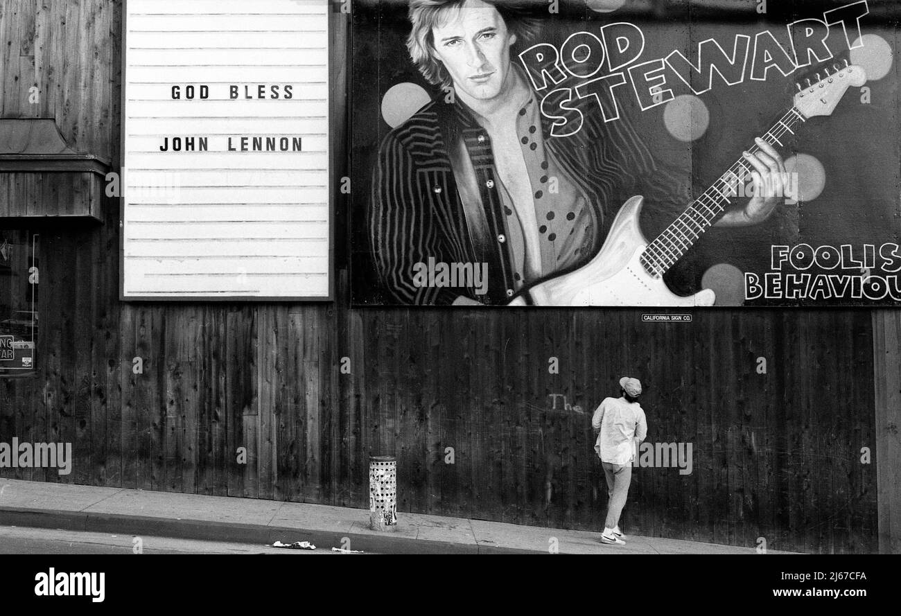 Schild zum Gedenken an den Tod von John Lennon im Jahr 1980 neben einer Plakatwand für Rod Stewart an der Seite des Licorice Pizza Plattenladens am Sunset Strip. Stockfoto