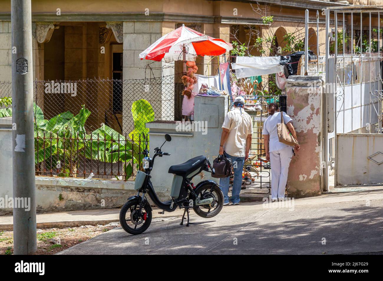 Zwei Kubaner stöbern in einem kleinen Geschäft, das auf einem Hinterhof des Hauses liegt. Rechts trägt die Frau eine Krankenschwester-Uniform. Eine elektrische Stockfoto