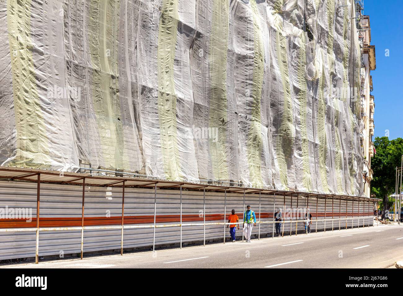 Baustelle in der Innenstadt. Ein metallischer Zaun und große Kleidung isolieren das Gebäude aus der Sicht von Fußgängern. Stockfoto