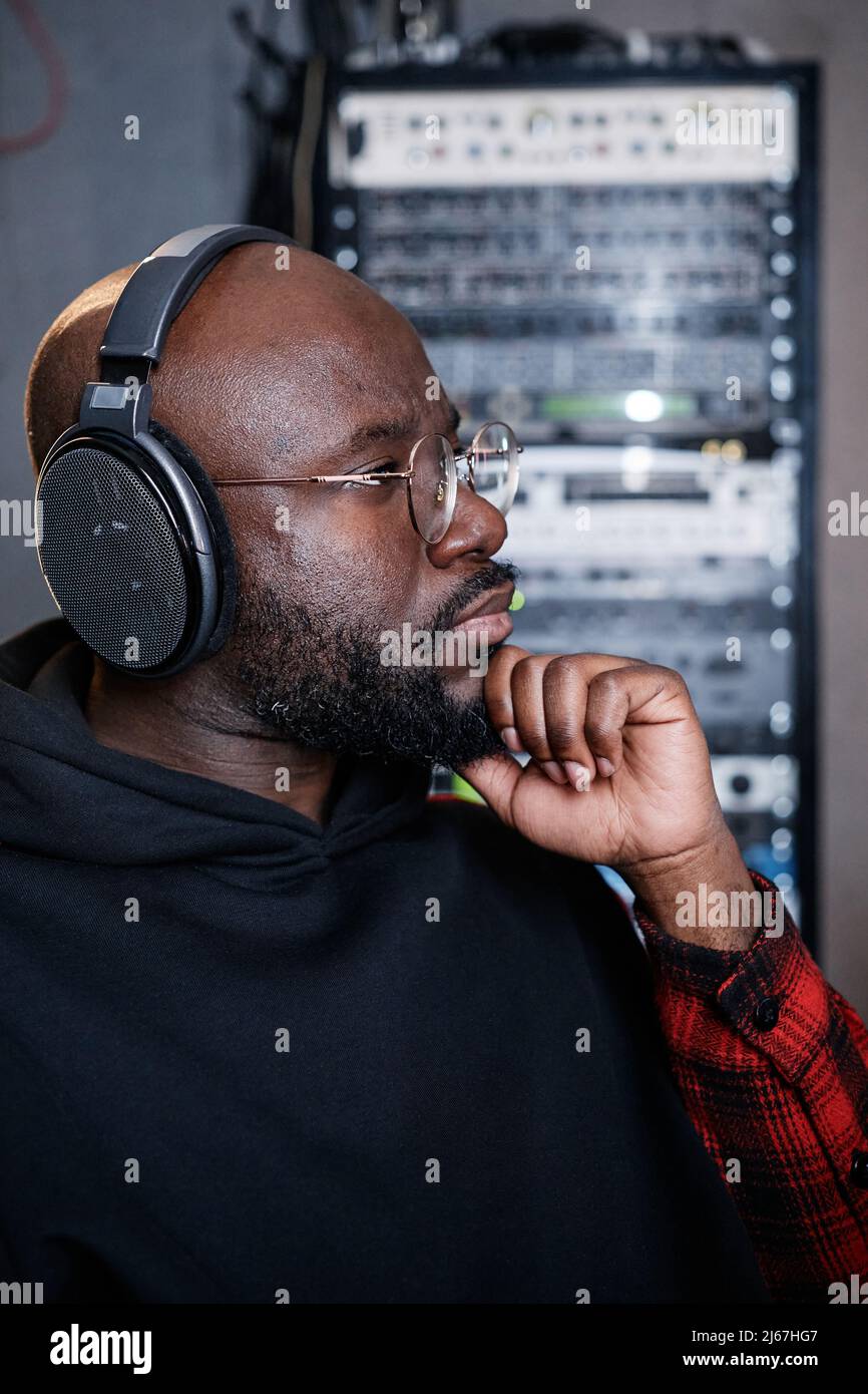 Porträt eines ernsthaften reifen schwarzen Mannes mit Bart im Gesicht, der im Aufnahmestudio arbeitet und Track hört Stockfoto