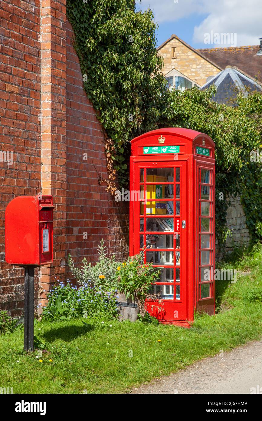 Rote englische Briefkasten und Telefonkiosks werden jetzt als Bücheraustausch genutzt und enthalten den Dorf-Defibrillator im Weiler Grafton Worcestershire Stockfoto