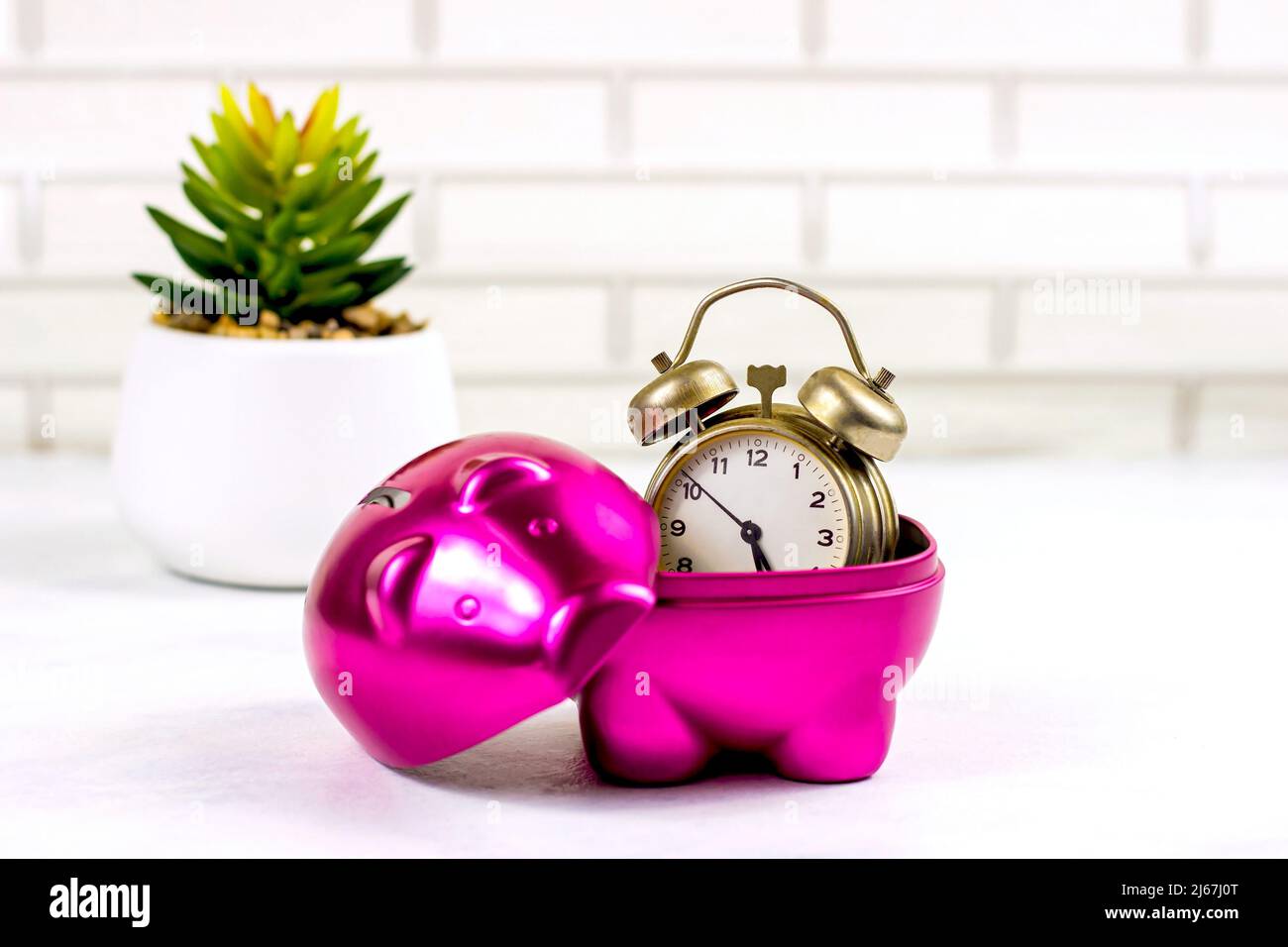 Pinkes Sparschwein-Münzbank mit Retro-Uhr innen auf hellem Hintergrund. Zeitersparnis und Managementkonzept. Stockfoto