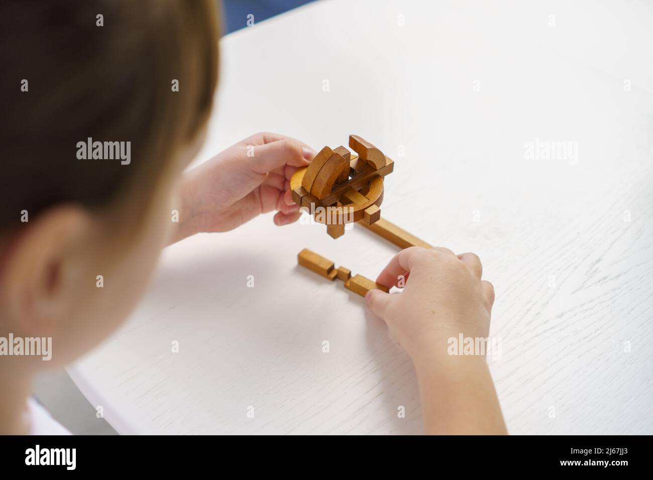 Kleines Mädchen spielt zu Hause mit hölzernen Puzzle-Blöcken. Konzept für die Entwicklung und Bildung von Kindern Stockfoto