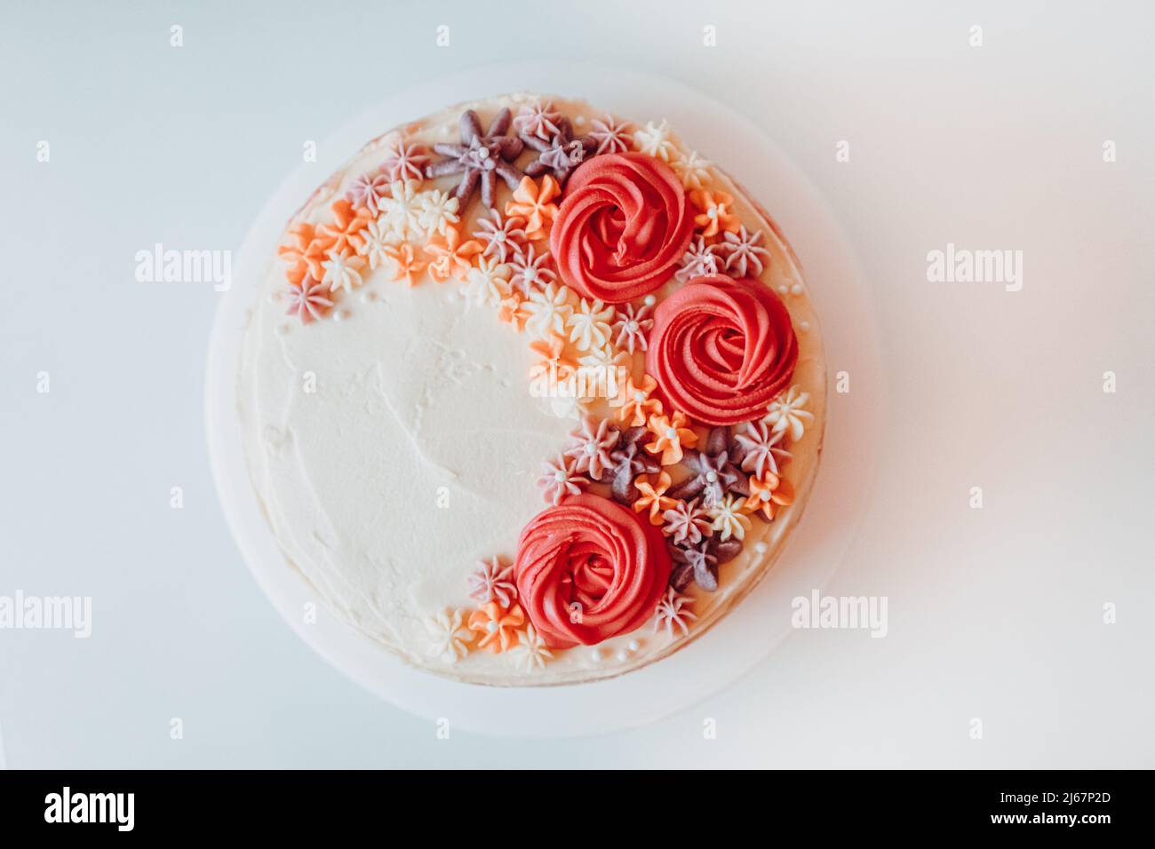 Hausgemachter klassischer Vanillemarmor-Sahnetorte, bestreut mit cremigen Blumendekorationen auf einem weißen Teller, Retro-Rustikale Farbdekoration und Ornamenten Stockfoto