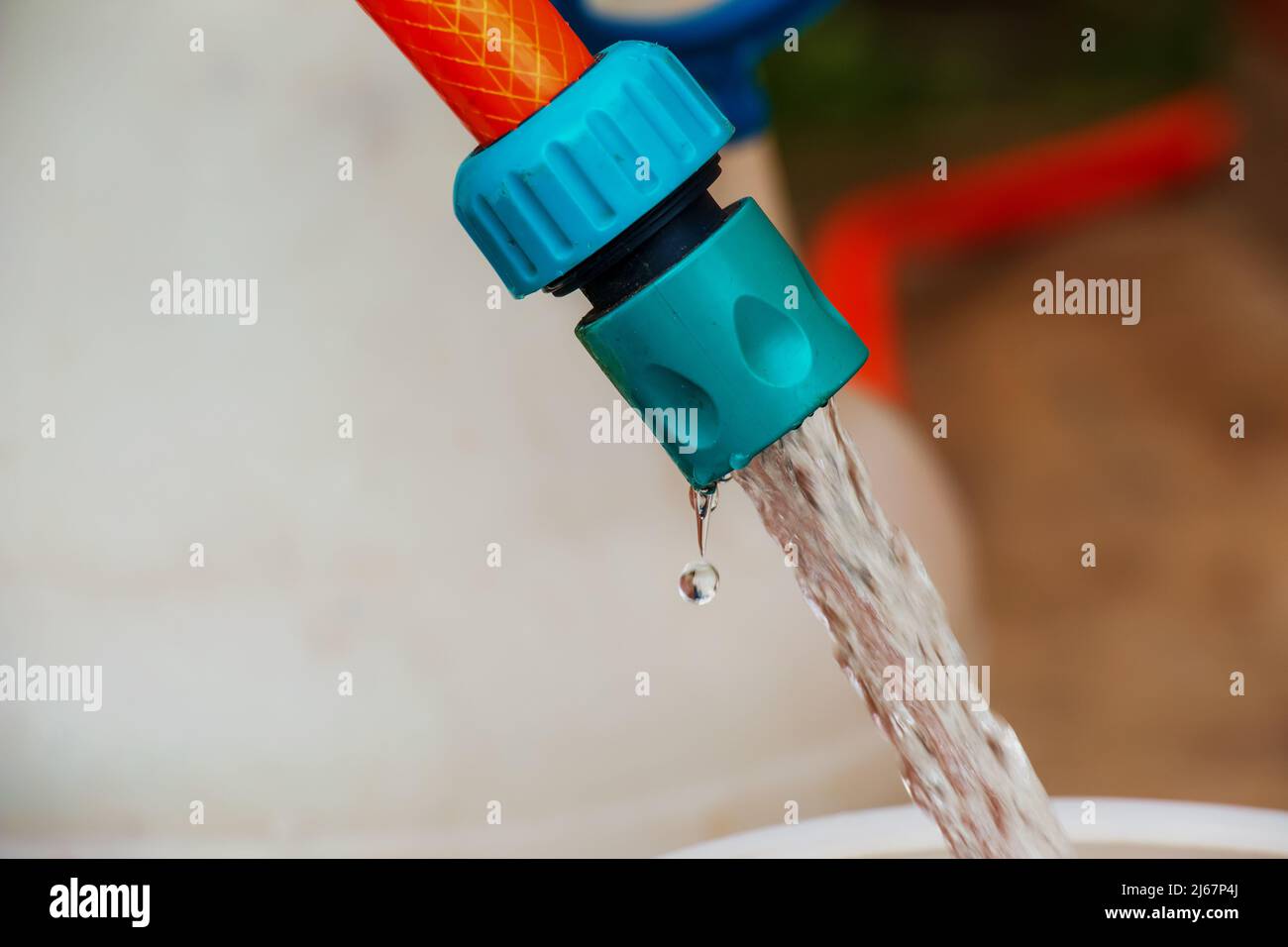 Ein Wasserstrahl aus einem Schlauch füllt ein Kunststofffass. Hintergrundbild. Das Konzept der Trinkwasserkrise in der Welt. Stockfoto