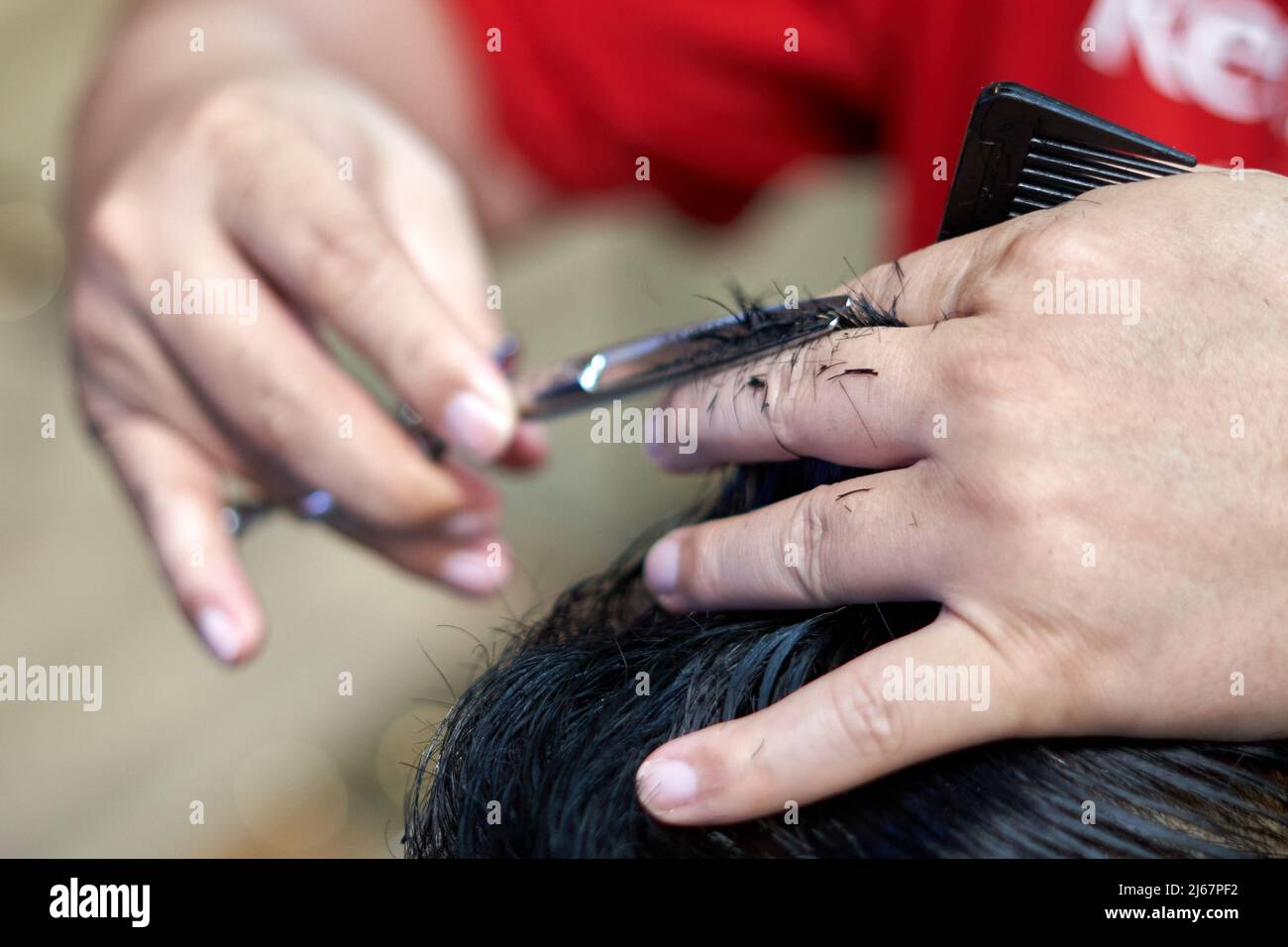 Barber schneidet die Haare eines Mannes mit einer Schere Stockfoto