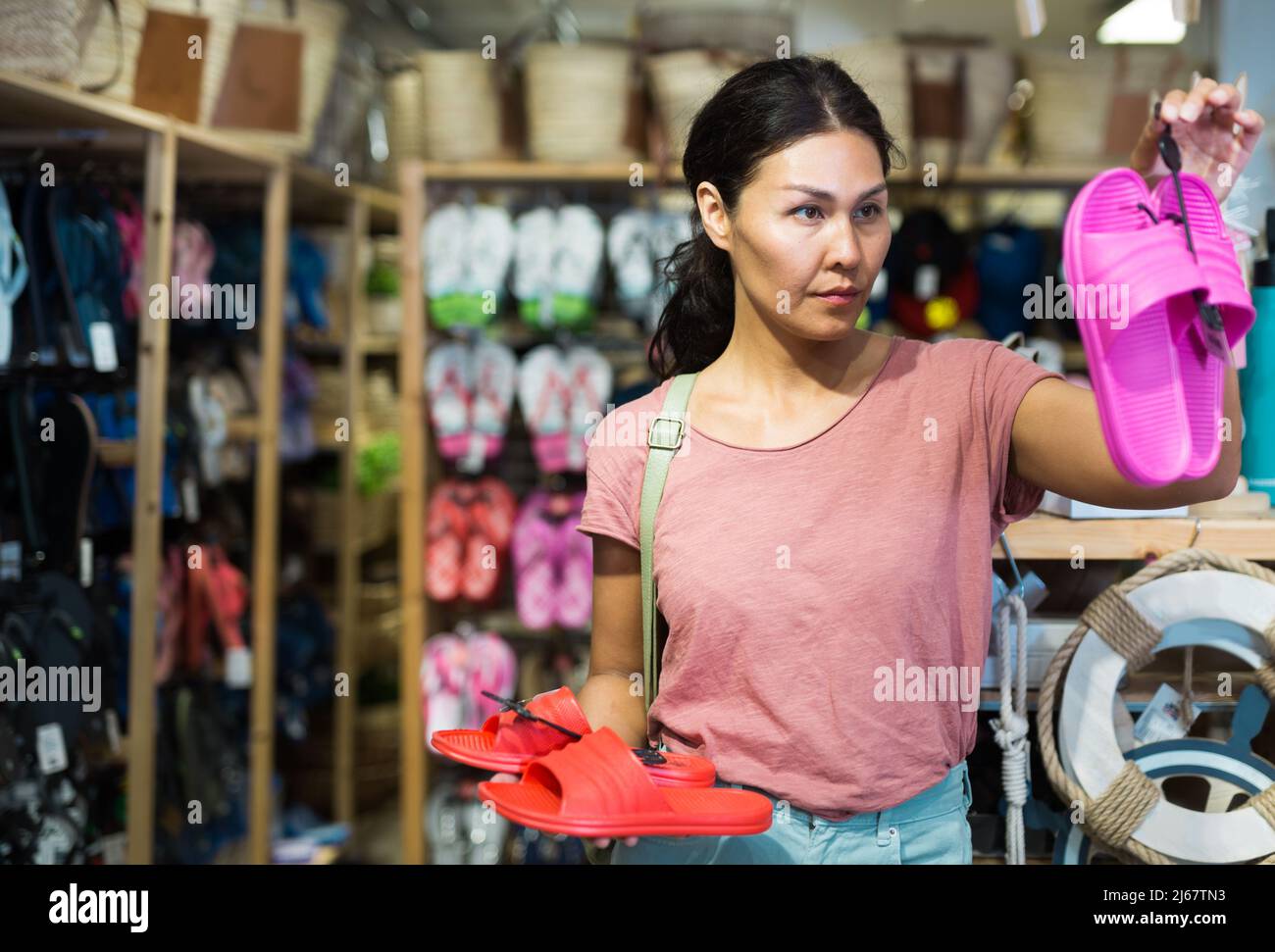 Weibliche Shopper wählt Strandflipflops im Baumarkt Stockfoto