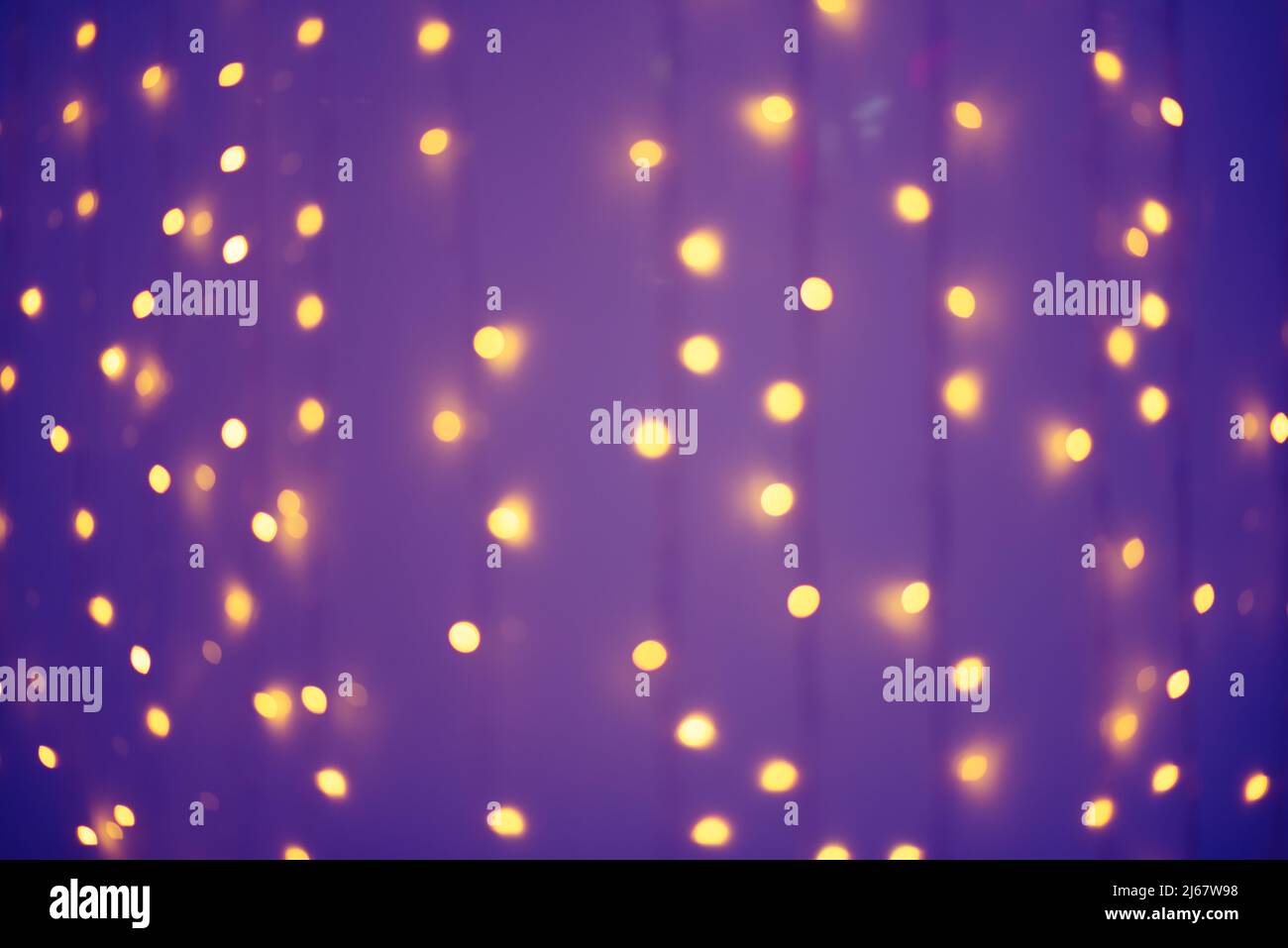 Verschwommenes Abstrakt: Verschwommene orangefarbene Girlanden auf dem violetten Hintergrund. Stockfoto