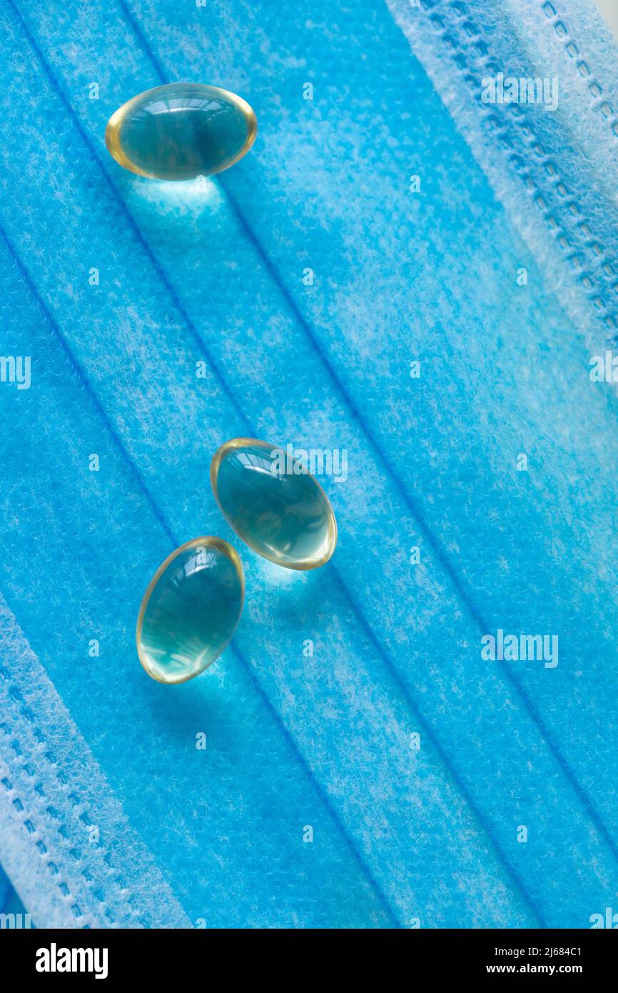 Blaue Einwegmasken, Softgel oder Kapsel der öligen Medizin und Medizin-Flaschen - Stock Foto Stockfoto