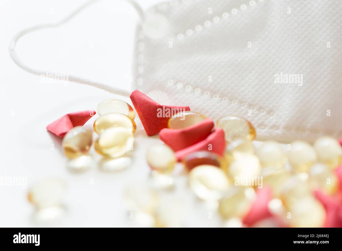Rotes herzförmiges Origami, weiche Kapsel Softgel und N95 Gesichtsmaske auf weißem Hintergrund - Stock Foto Stockfoto