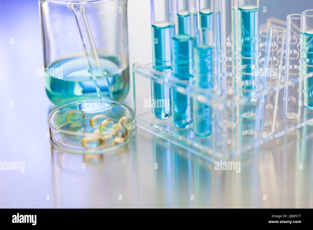 Glasschale mit weichen Kapseln in einem CHEMIELABOR mit Becher und Reagenzglasgestell - Stock Foto Stockfoto