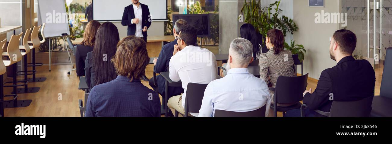 Rückansicht von Personen, die sich in einer Geschäftsausbildung befinden, und dem männlichen Coach zuhören, der Mitarbeiter vorhält und ausbildet. Stockfoto