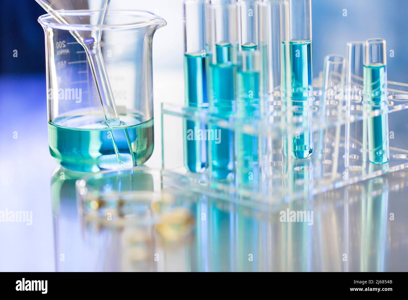 Blaues chemisches Reagenz im Becher mit Glastrichter und Reagenzglasgestell - Stock Photo Stockfoto