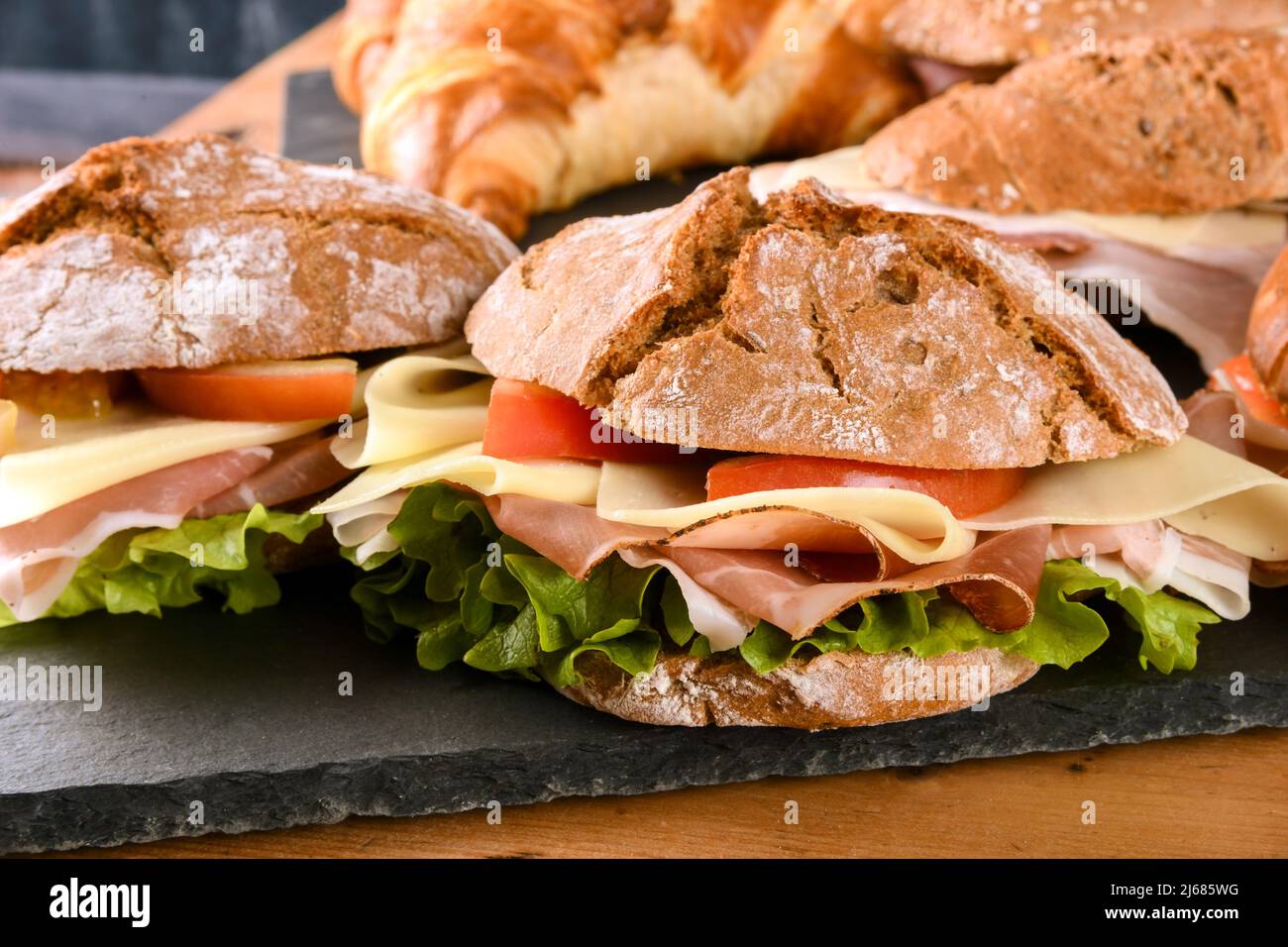 Leckere Sandwiches aus frischem Gemüse mit Brötchen und Schinken mit Käse, die an Bord im Restaurant serviert werden Stockfoto