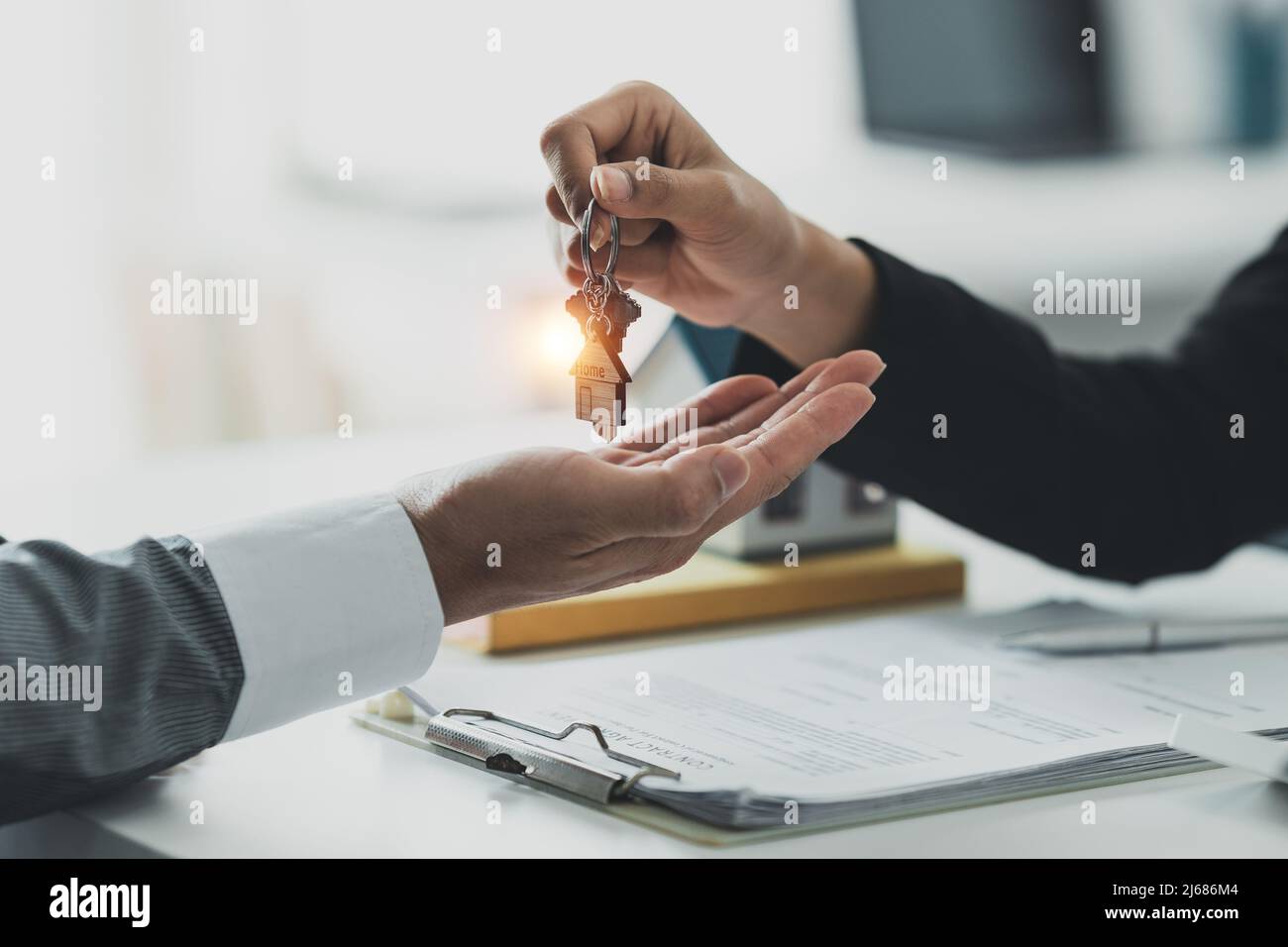 Nahaufnahme Geschäftsmann oder Immobilienmakler geben Hausschlüssel nach der Unterzeichnung Vereinbarung für den Kauf von Haus. Bankmanager und Immobilienkonzept. Stockfoto