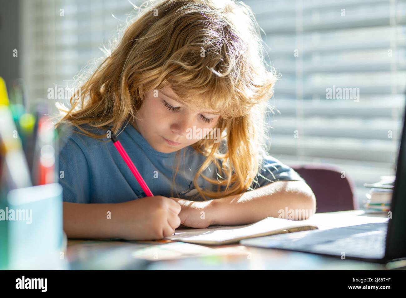 Kind schreibt in der Schule. Lustige Kind Mädchen tun Hausaufgaben schreiben und lesen zu Hause. Kleiner Schüler am Schreibtisch im Klassenzimmer. Stockfoto