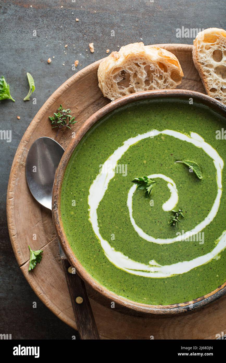 Frische grüne Suppe mit Creme auf grauem Hintergrund über dem Schuss. Stockfoto