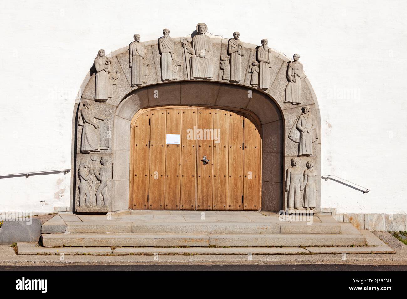 Vannas, Norrland Schweden - 7. August 2021: kirchentor mit interessanten Steinfiguren im Relief Stockfoto