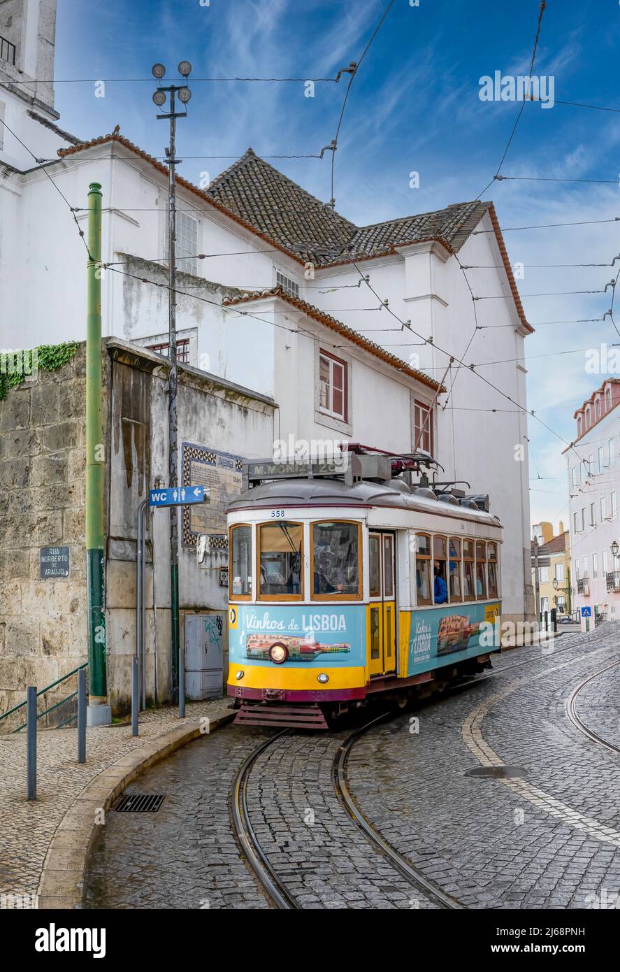 Eine fabelhafte alte gelbe Straßenbahn schlängelt sich durch die kopfsteingepflasterten Straßen von Lissabon, Portugal Stockfoto