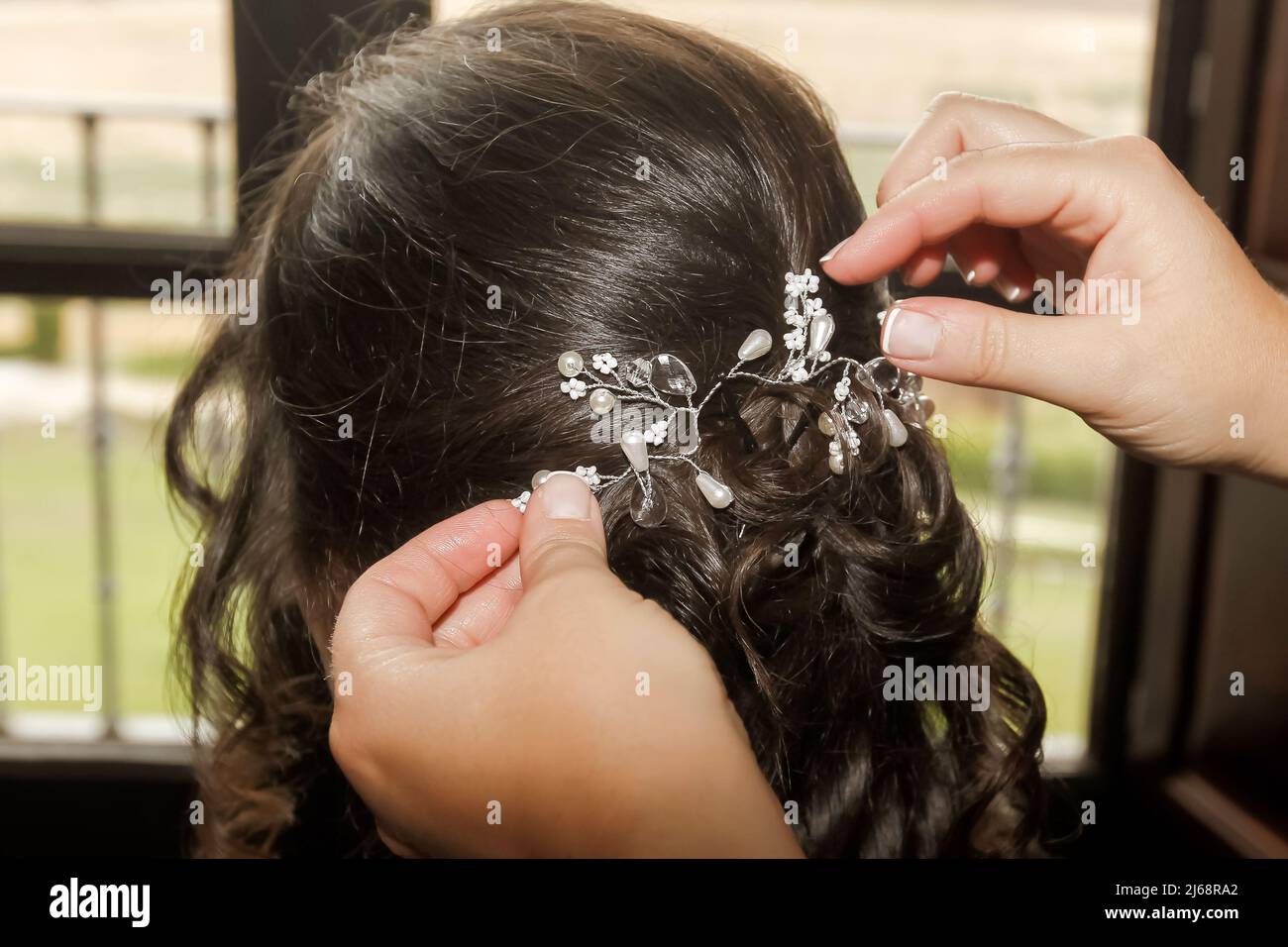 Schöner Haarschmuck, der auf den Kopf einer Frau mit dunklem Haar gelegt wird. Stockfoto