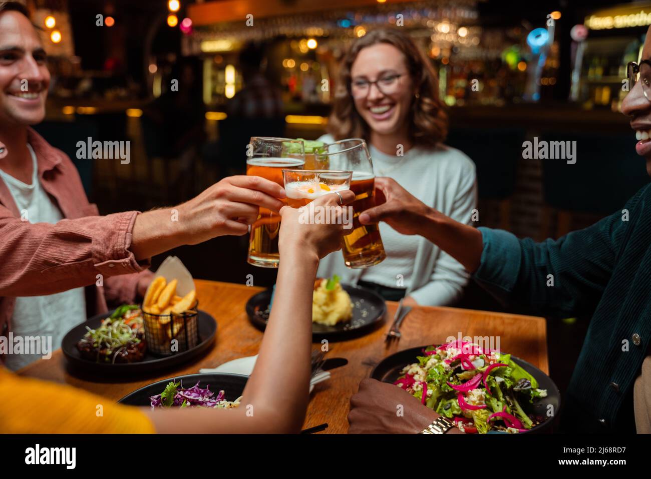 Eine Gruppe verschiedener Freunde zum Abendessen, die mit Cocktails anstoßen Stockfoto