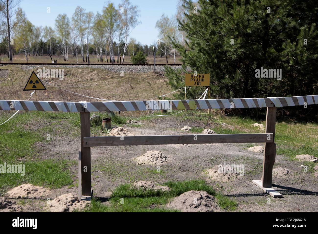 Tschernobyl, Ukraine. 28. April 2022. Im Roten Wald in der Tschernobyl-Sperrzone nach dem Abzug der russischen Truppen, Region Kiew, Nordukraine, am 28. April 2022, sind ein internationales ionisierendes Strahlungsdreieschesymbol und das Schild mit der Aufschrift "Roter Wald" abgebildet. Russische Truppen haben das Gebiet um Tschernobyl verlassen, aber ukrainische Beamte machen jetzt Alarm, dass Truppen wahrscheinlich hohen Strahlenmengen ausgesetzt waren, nachdem sie absichtlich radioaktiven Staub gestört hatten. Mitarbeiter des Kernkraftwerks Tschernobyl (NPP), dem Ort der Atomkatastrophe von 1986, haben vor f gewarnt Stockfoto