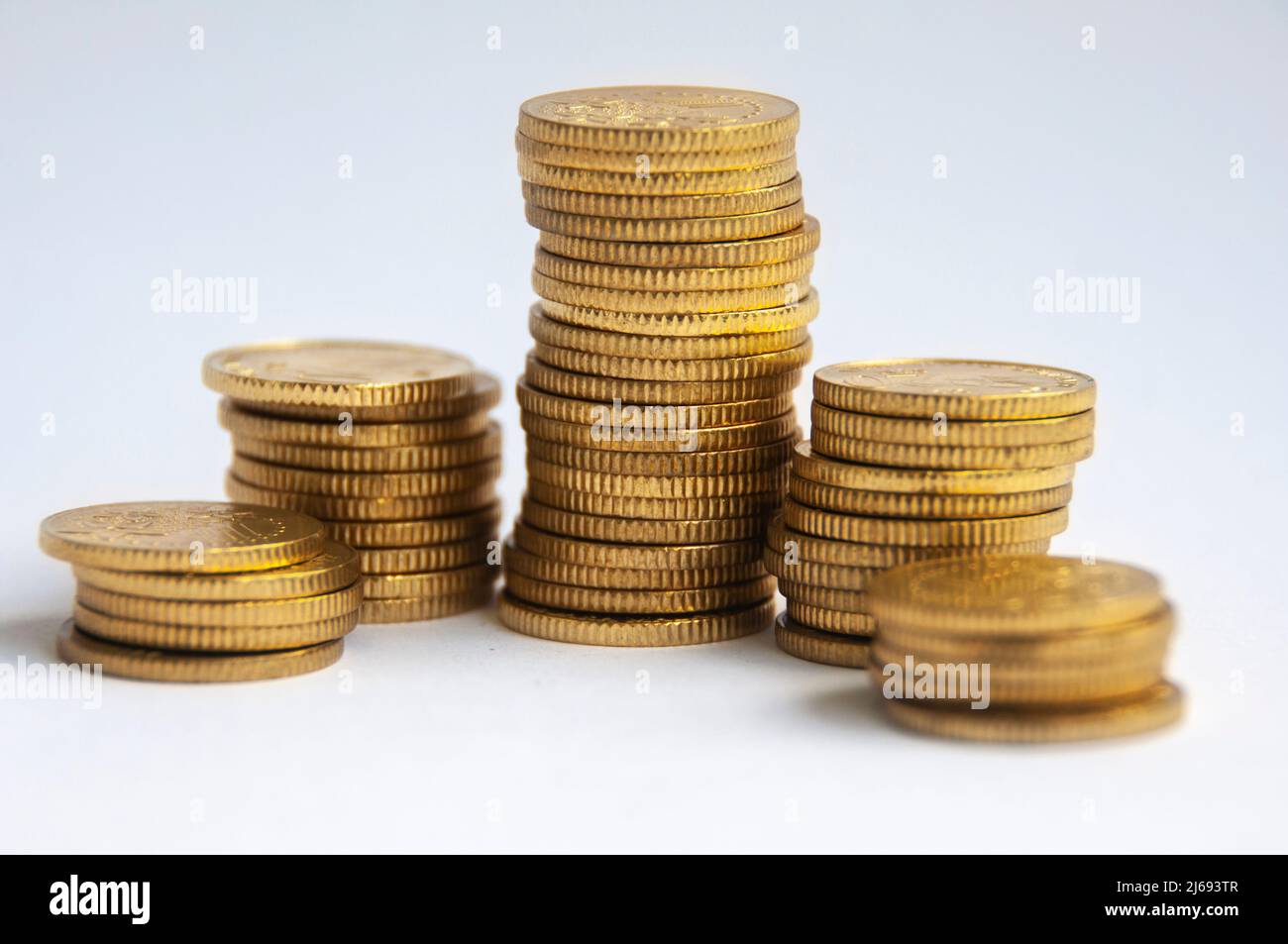 Goldmünzen auf weißem Hintergrund gestapelt. Finanz- und Kopierraumkonzept Stockfoto