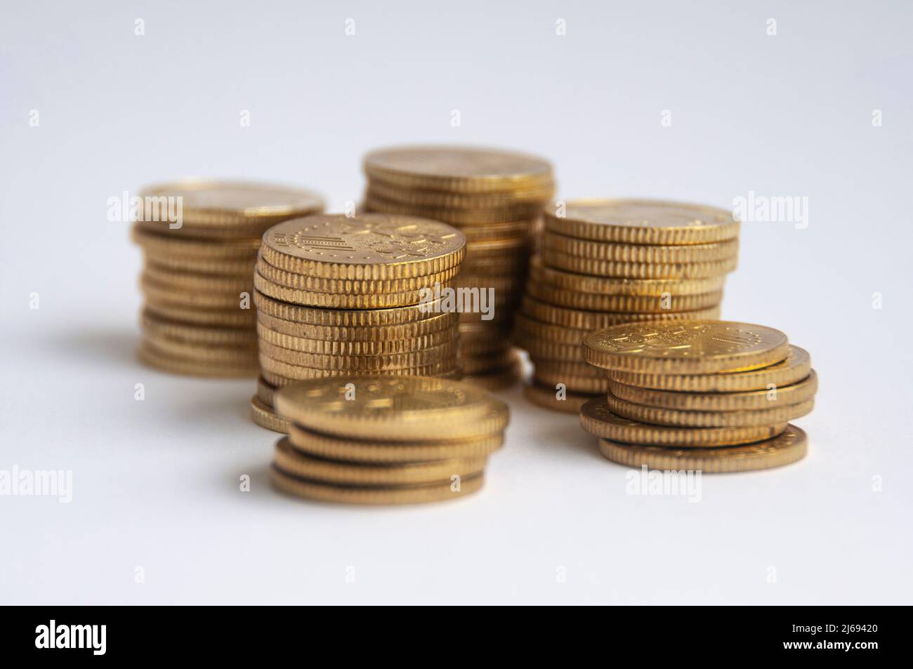 Goldmünzen auf weißem Hintergrund gestapelt. Finanz- und Kopierraumkonzept Stockfoto