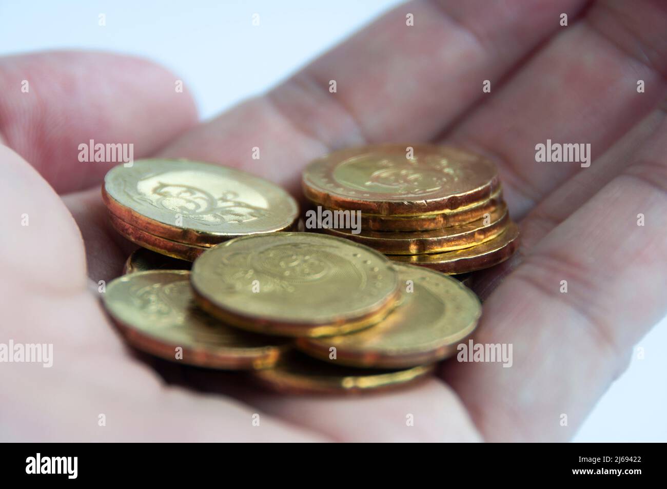Hand zeigt Goldmünzen mit weißem Hintergrund. Stockfoto