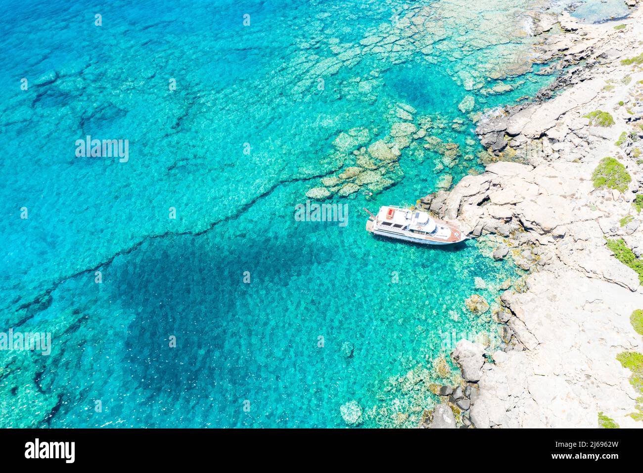 Luftaufnahme der Yacht, die im kristallklaren Meer, auf Kreta, auf den griechischen Inseln, in Griechenland festgemacht ist Stockfoto