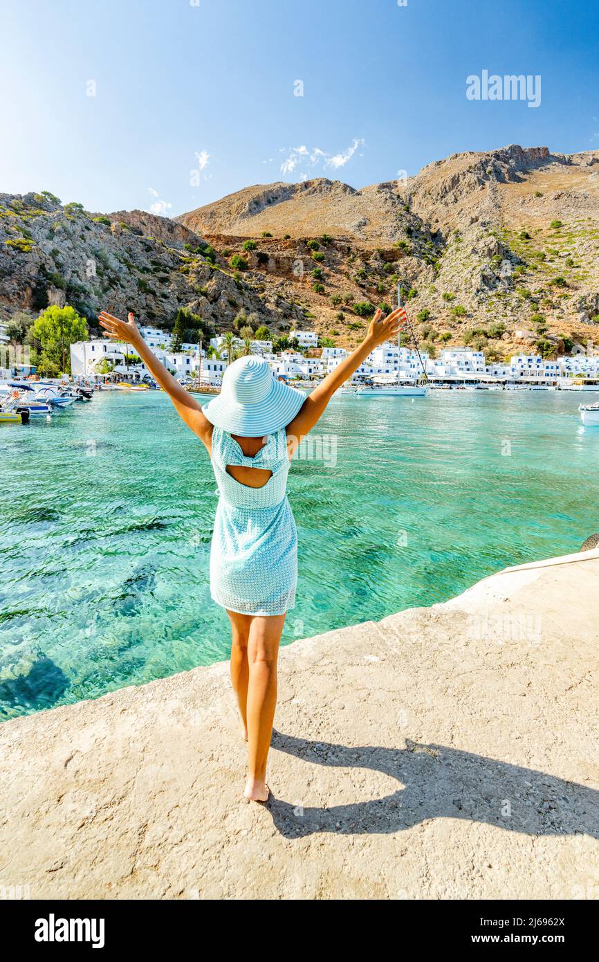 Fröhliche Frau mit Sonnenhut, die das Dorf Loutro und das kristallklare Meer, die Insel Kreta, die griechischen Inseln, Griechenland bewundert Stockfoto