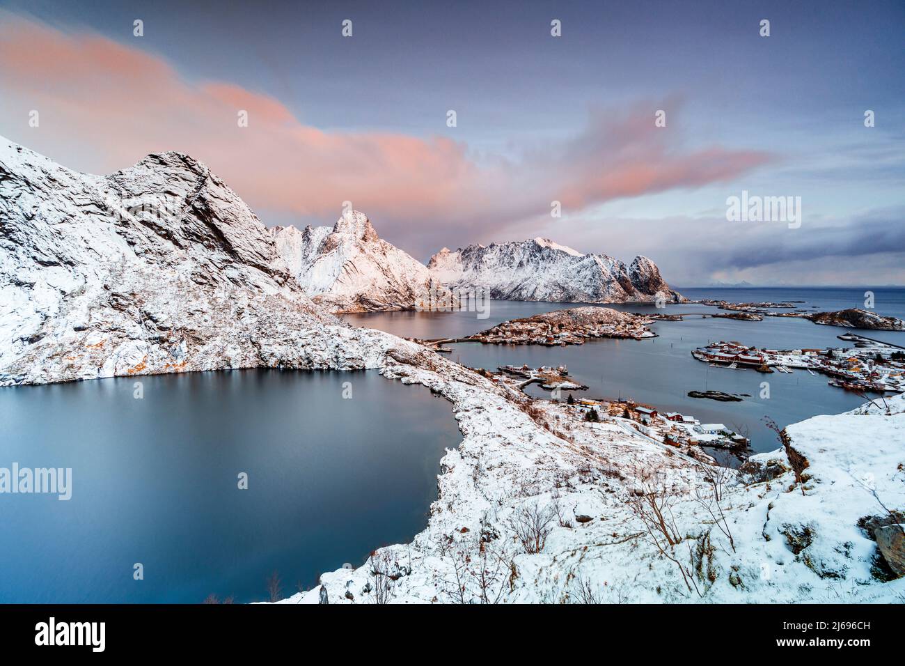 Luftaufnahme des gefrorenen Reinevatnet-Sees, der reine Bay und des schneebedeckten Olstind-Berges in der Morgendämmerung, der Lofoten-Inseln, Norwegens, Skandinaviens, Europas Stockfoto