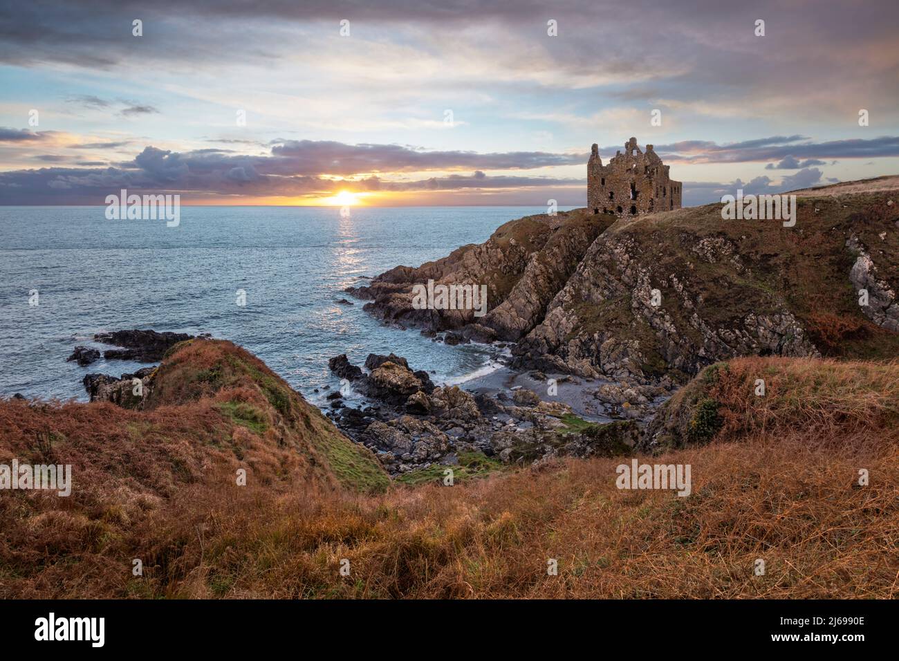 Ruinen von Dunskey Castle an zerklüfteter Küste bei Sonnenuntergang, Portpatrick, Dumfries und Galloway, Schottland, Vereinigtes Königreich, Europa Stockfoto