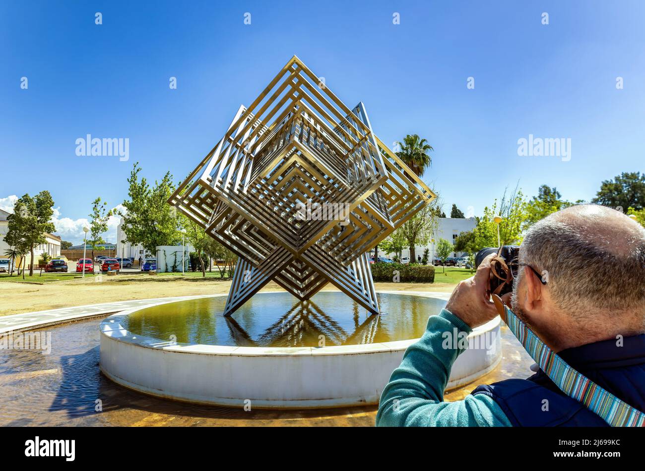 Huelva, Spanien - 28. April 2022: Ein Fotograf, der ein Foto des Edelstahlwürfels in den Gärten des Campus de „El Carmen“ des H macht Stockfoto