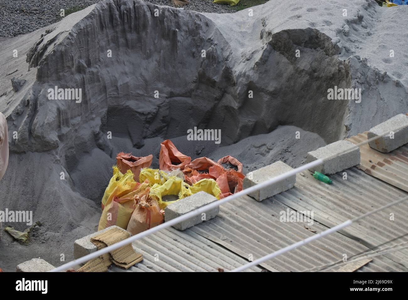 Stapel aus M-Sand und gebrauchten Zementsäcken, gefüllt mit Sand und Betonsteinen auf einer Baustelle Stockfoto