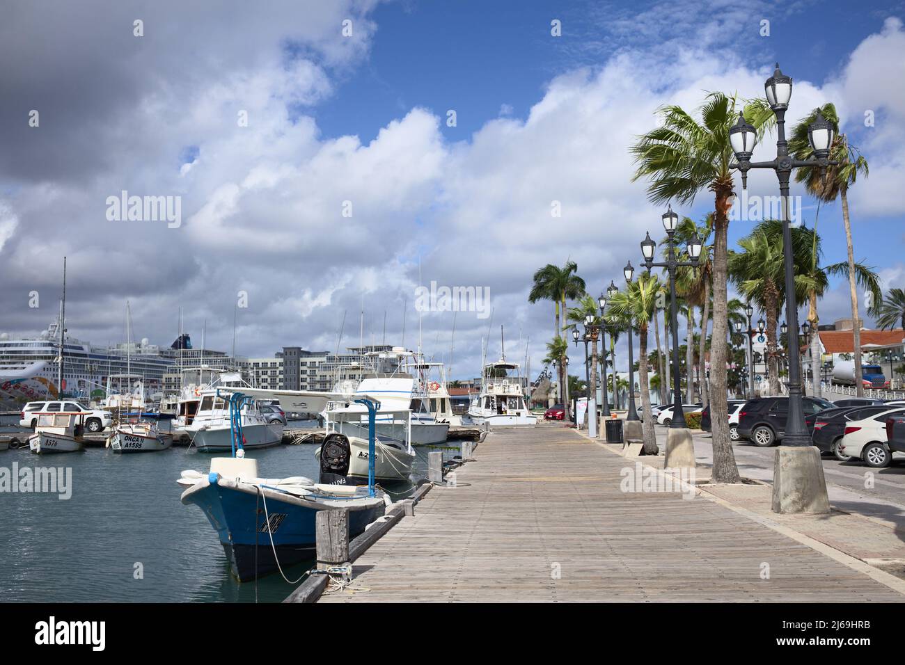 ORANJESTAD, ARUBA - 14. DEZEMBER 2020: Fischerboote in der Wind Creek Marina, links hinten das Norwegian Pearl-Schiff in Oranjestad, Aruba Stockfoto