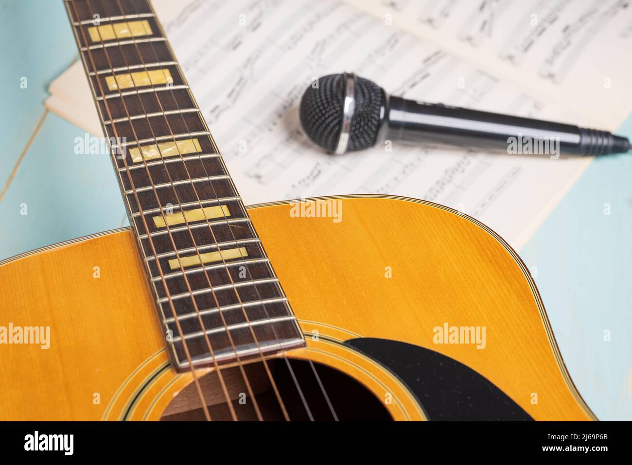 Musikaufnahme-Szene mit Gitarre, Notenblättern und schwarzem Mikrofon auf Holztisch Stockfoto