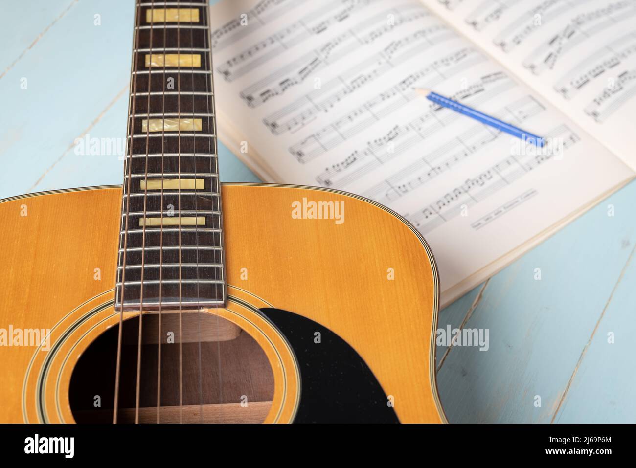 Musikaufnahme-Szene mit Gitarre, Notenblatt und Bleistift auf Holztisch, Nahaufnahme Stockfoto