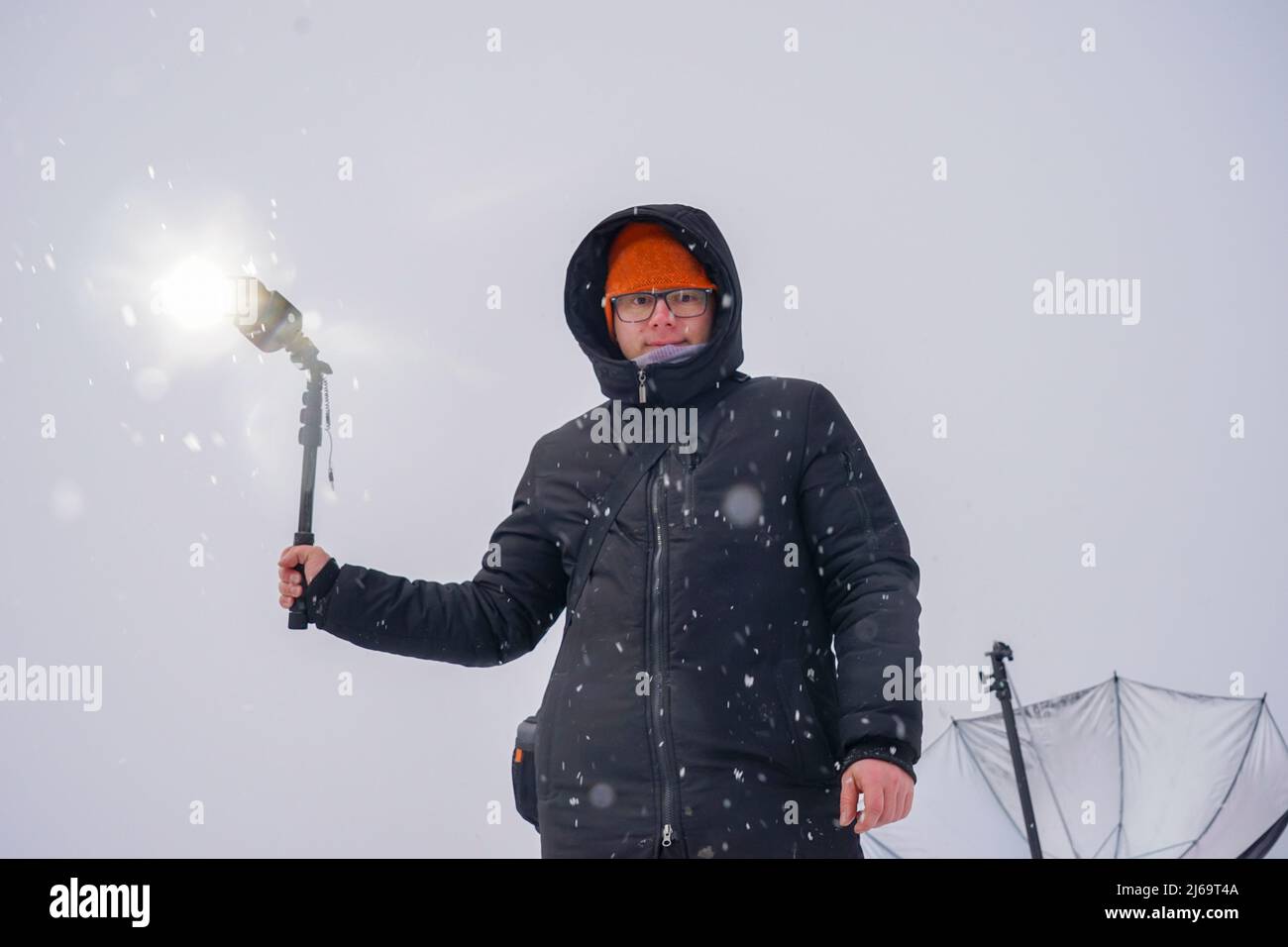 Ein Outdoor-Fotograf hält einen Studioblitz in den Händen. Aufnahmen in der Natur Stockfoto